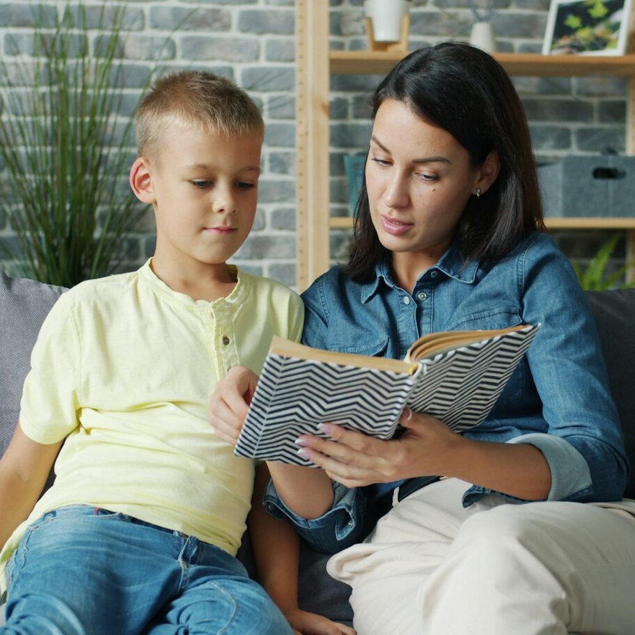 A mom reading a book with her son on the couch